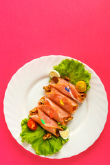 Ham rolls on a plate with green salad near eggs on a mantle background. on a white plate