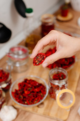 Sun-dried tomatoes. The process of cooking sun-dried tomatoes. The woman is preparing tomatoes in the kitchen. A woman cuts tomatoes, greases them with oil and spices them. 