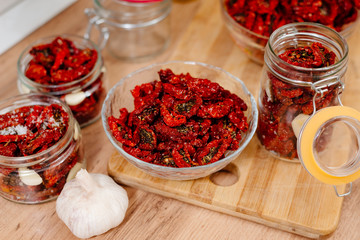 Sun-dried tomatoes. The process of cooking sun-dried tomatoes. The woman is preparing tomatoes in the kitchen. A woman cuts tomatoes, greases them with oil and spices them. 