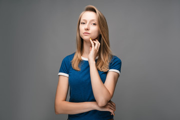 Thoughtful young female looking confident at the camera with hand raised on chin. Concept of thinking