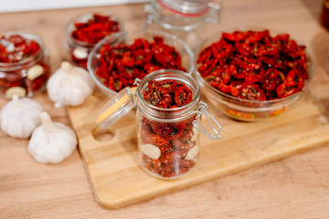 Sun-dried tomatoes. The process of cooking sun-dried tomatoes. The woman is preparing tomatoes in the kitchen. A woman cuts tomatoes, greases them with oil and spices them. 