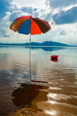 Multicolor umbrella in sand on a lake. Beautiful landscape of nature