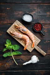 Scampi on cutting board on old wooden dark table, top view