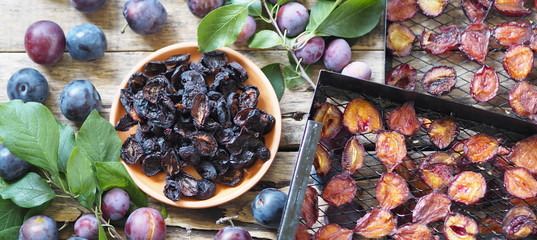 Fruit plum chips. Black grates from a home fruit and vegetable dryer with dried plums on a wooden...