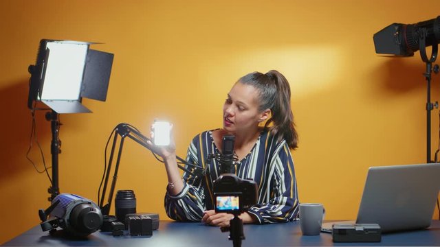 Influencer presenting a mini-led light for professional use in her studio. Video blogger recording a vlog with technology product equipment use in videography and photography