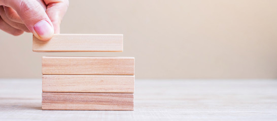 Businessman hand placing or pulling wooden block on the tower. Business planning, Risk Management, Solution, Insurance and strategy Concepts