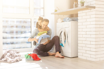 Happy family man father householder and child daughter in laundry with washing machine