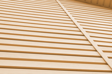 Striped plastic siding surface and piece of cornice. Construction and renovation of buildings. Tinted light brown background or wallpaper. Building materials or technologies
