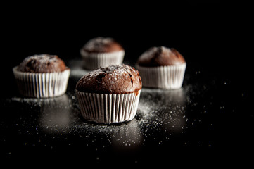 muffin dessert on a black background with sugar powder. Side view.