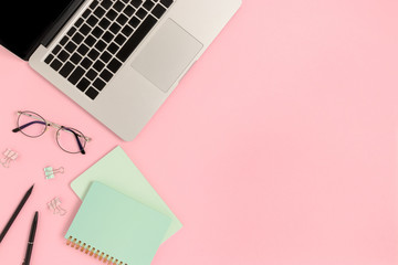 Top view of laptop and stationery on a pink pastel background. Workspace concept with copy space.