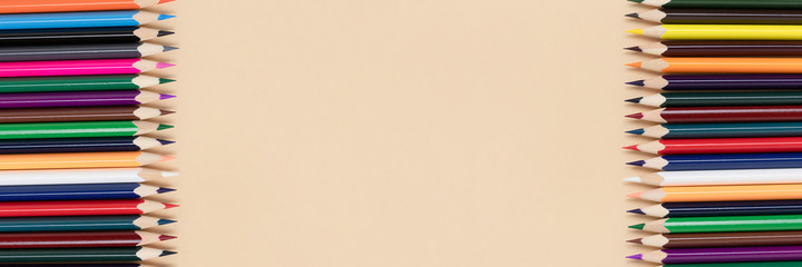 Frame made of colorful pencils on a beige background. Banner with back to school concept.