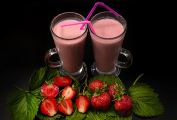 Strawberry smoothie on a black background with berries and strawberry leaves