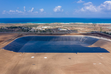 Water reservoir construction site with newly installed plastic lining sheets, Aerial view.