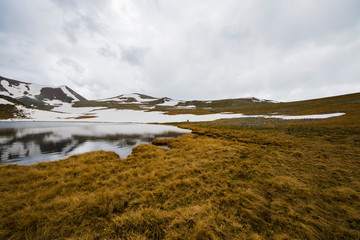 Alpine mountain lake landscape at the daytime, colorful landscape, snow and clouds