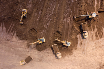 Vast Excavation site with an on going operation of Excavators loading soil onto Trucks, Aerial view.
