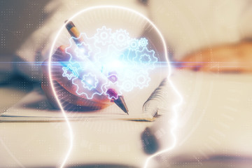 Double exposure of woman's writing hand on background with brain hologram. Concept of brainstorming.