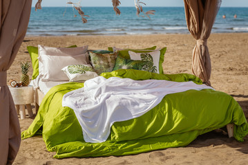 Cozy bed on a beach in green bed linen