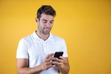 Young man having a conversation using smartphone over yellow background with a happy face standing and smiling with a confident smile showing teeth
