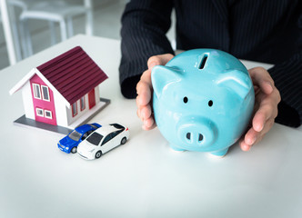 Business woman protecting  piggy bank in hand, saving money for invest in house and cars or buy new house and car, copy-space white background,