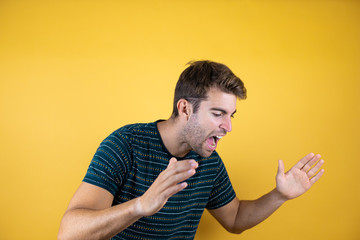 Young fitness man over yellow isolated background shouting and screaming loud to side with hand on mouth. Communication concept.