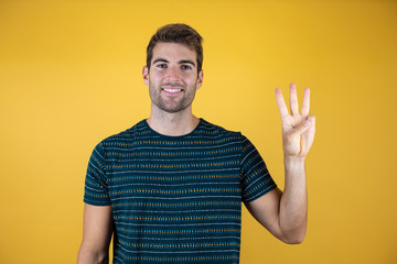 Young handsome man wearing casual blue t-shirt over yellow isolated yellow background showing and...