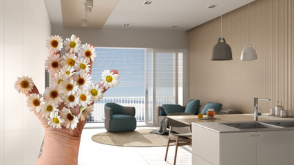 Woman's hand holding daisies, spring and flowers idea, over modern minimalist living room with kitchen, wooden and concrete walls, panoramic window, lamp, parquet, interior design