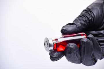 Fototapeta premium A woman's hand in black gloves holds an ampoule. Vaccine. The ampoule with the medicine. Medication for injection.