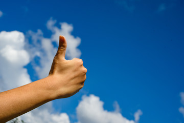 Thumb up in the sky. Hand show thumbs up on a blue sky