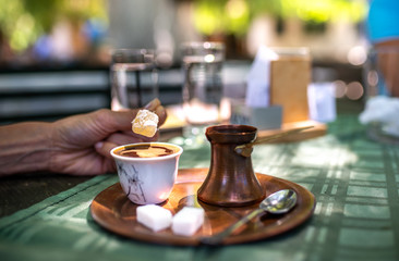 Traditional turkish black coffee and sweet lokum dessert on a table in a restaurant. Enjoying oriental flavors from authentic pots.