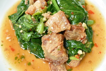 spicy fried Chinese kale with slice crispy pork in soybean and oyster sauce on plate