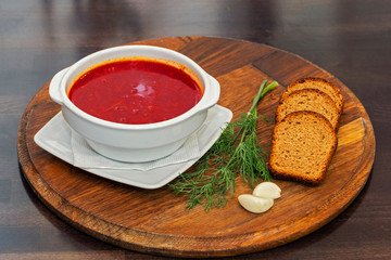 Ukrainian borsch with beets, pieces of black bread, garlic and dill on a wooden background. Beetroot soup. Ukrainian folk cuisine. Ukrainian dish. Top view.