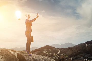 Businesswoman standing against landscape and making selfie