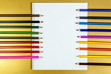 Colored pencils lie on a white notebook sheet.