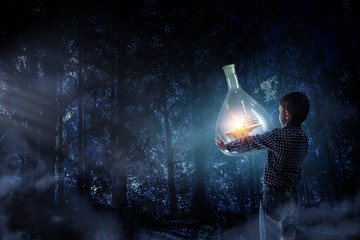 Boy holding glass flask with landscape inside it