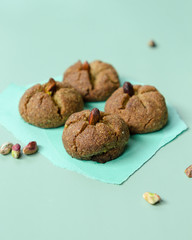 Traditional homemade Moroccan festive ghoriba cookies with pistachio nuts on trendy mint color background.