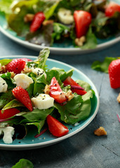 Goats cheese and strawberry summer salad served with nigella and sesame seeds drizzled with runny honey