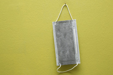 Method of coronavirus prevention using surgical mask. Surgical mask hanging on a wall with green background.