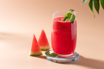 refreshing watermelon drink with mint in a glass and green leaves in the background. Summer detox juice. beige background. copy space