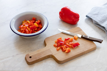 chopped red bell pepper with a knife on a wooden cutting board. cooking healthy diet food. light background.