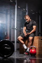 Muscular athlete with weightlifting equipment. Crossfit trainer in a fitness studio. Smoke background.