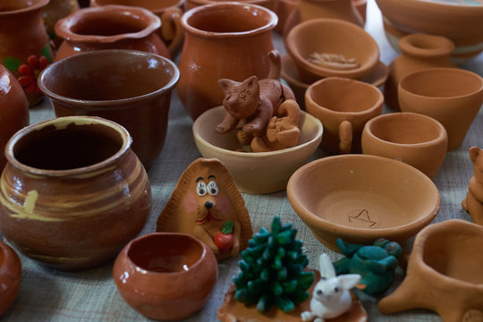 Many clay pot is on the table in pottery. Bright pottery. Many white, not painted clay pottery standing on wooden table. Creative studio potter. Workplace wizard Crock pottery