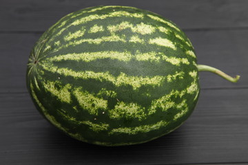 Striped watermelon on a dark wooden background.