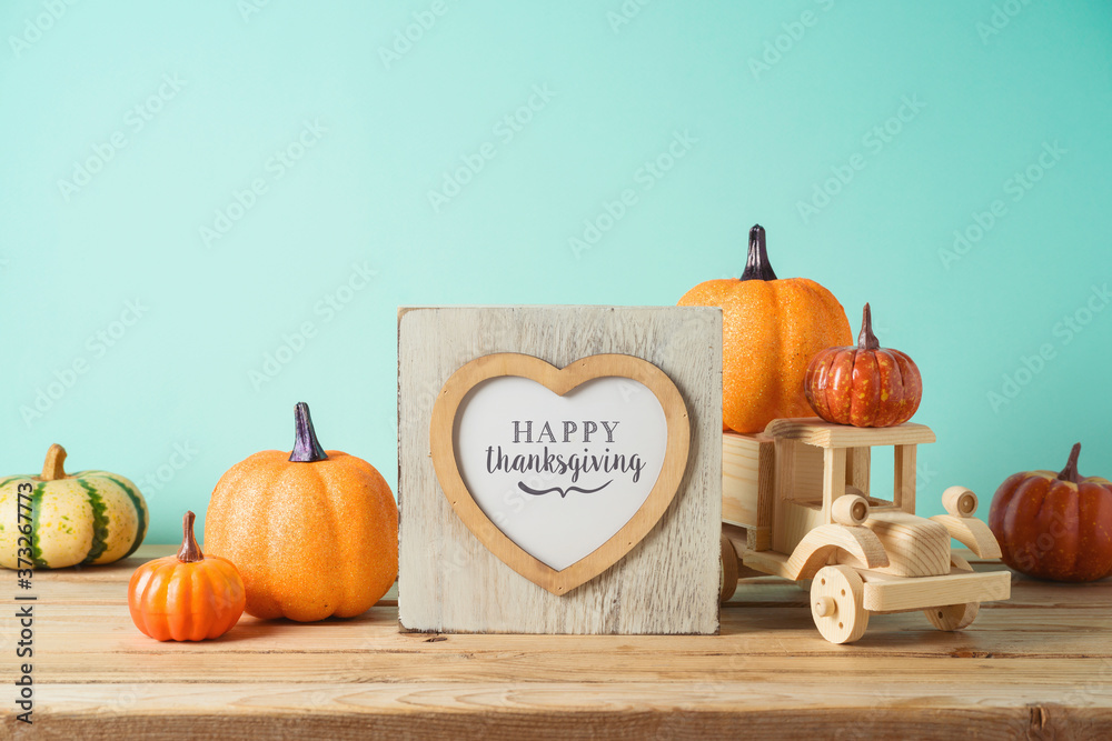 Wall mural happy thanksgiving concept with photo frame, toy truck and pumpkin decor on wooden table over blue b