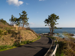 A view of the trail along the ocean with blue sky. The Michinoku Coastal Trail in Iwate Prefecture, Japan.