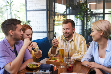 happy caucasian friends did not meet each other in a long time, hold meeting in restaurant or bar, have meal, discuss news