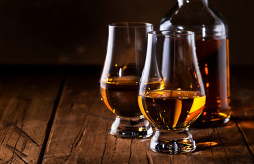 Scotch Whiskey without ice in glasses and bottle, rustic wood background, copy space