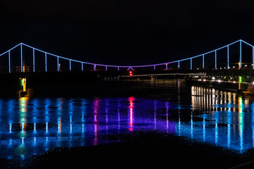 Bewitching color illumination of the bridge reflected in water at night