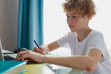 Fototapeta premium young boy studying at home, education concept. do homework, sit in bedroom, writing and reading