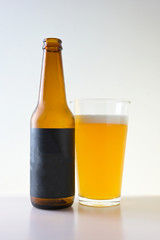 Glass and bottle of beer on white background with black blank label