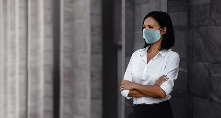 Portrait of a Mixed Races Business Woman, Wearing a Surgical Mask. Healthcare in New Normal Lifestyle Concept. Crossed Arm and Looking away - obrazy, fototapety, plakaty